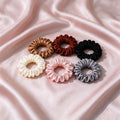 Six satin scrunchies laid out in an arc.