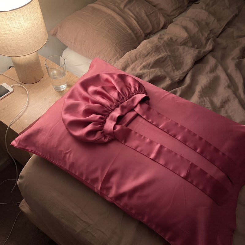 The satin bonnet laid flat on satin, its long tie band fully extended.